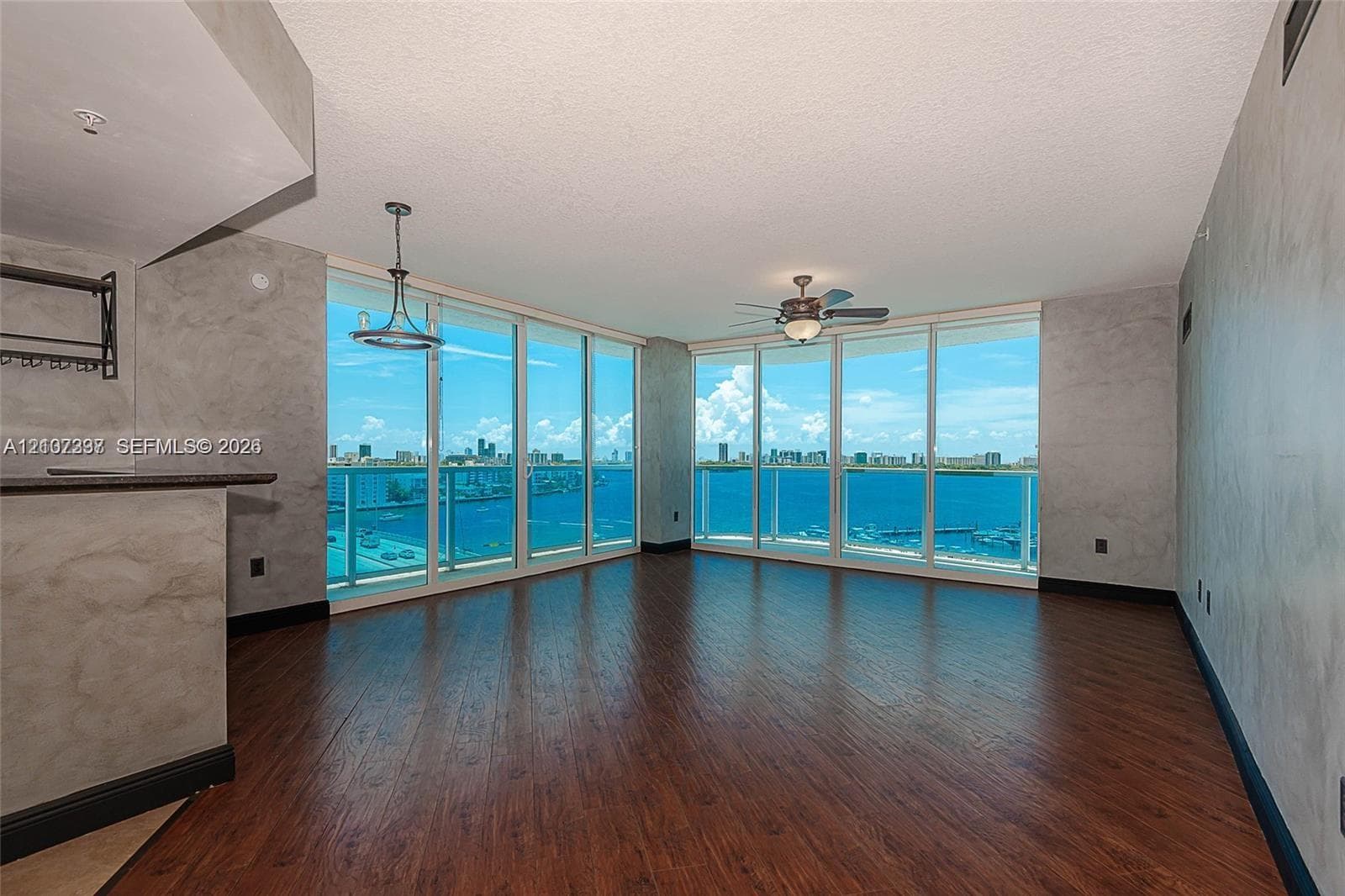 Living area featuring floor-to-ceiling glass windows, wood-finish flooring, textured wall finishes, and a contemporary pendant light fixture