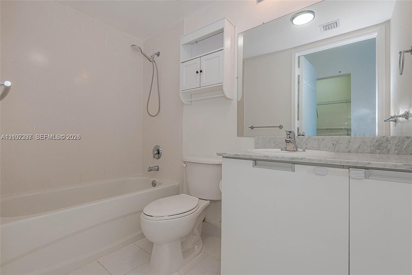 Bathroom featuring a vanity with stone-finish countertop, undermount sink, built-in storage cabinet, full-width mirror, and a tub-shower combination