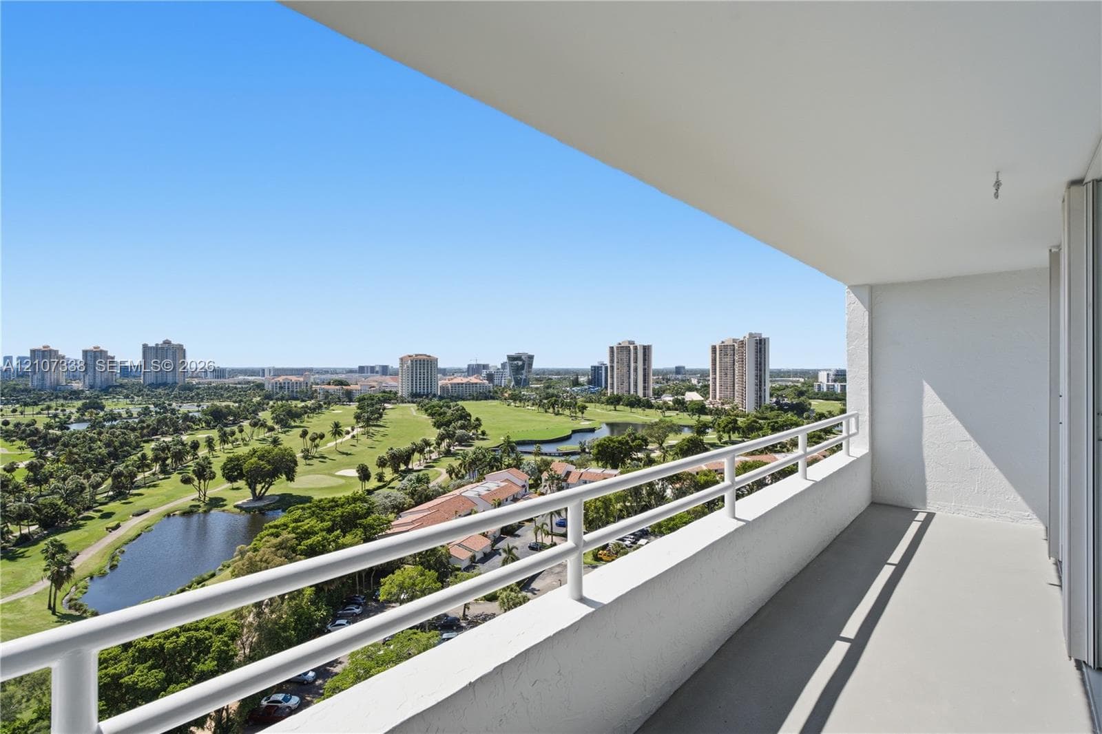 Covered balcony with white metal railings, concrete flooring, and unobstructed exterior exposure