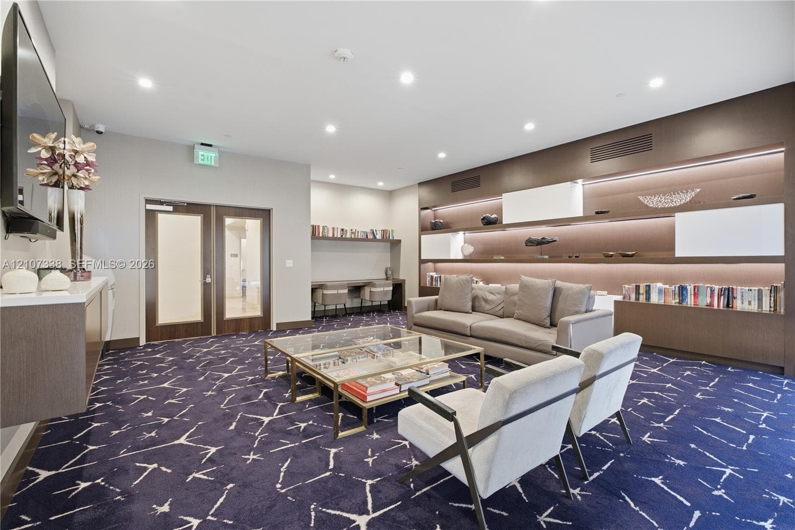 Large-format patterned carpeting, expansive wall-to-wall built-in shelving with integrated LED illumination, and a dedicated wood-finish desk workstation