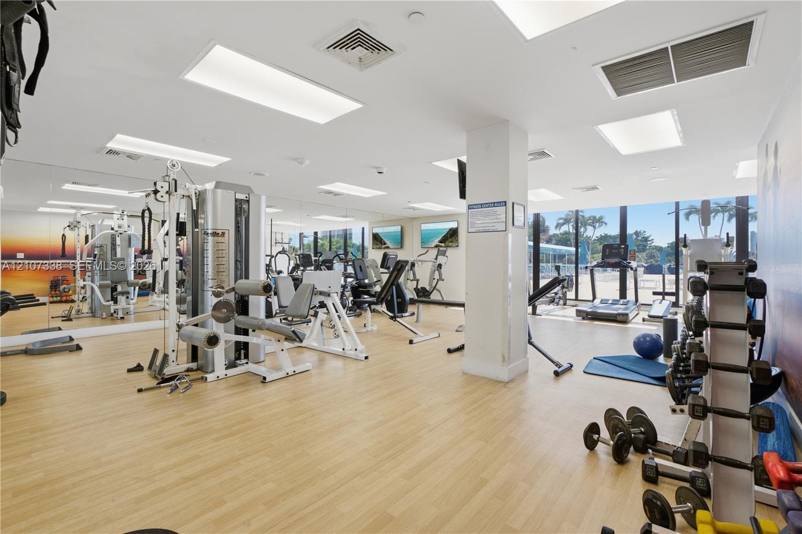 Fitness center featuring wood-finish flooring, full-length wall mirrors, recessed lighting, and floor-to-ceiling windows
