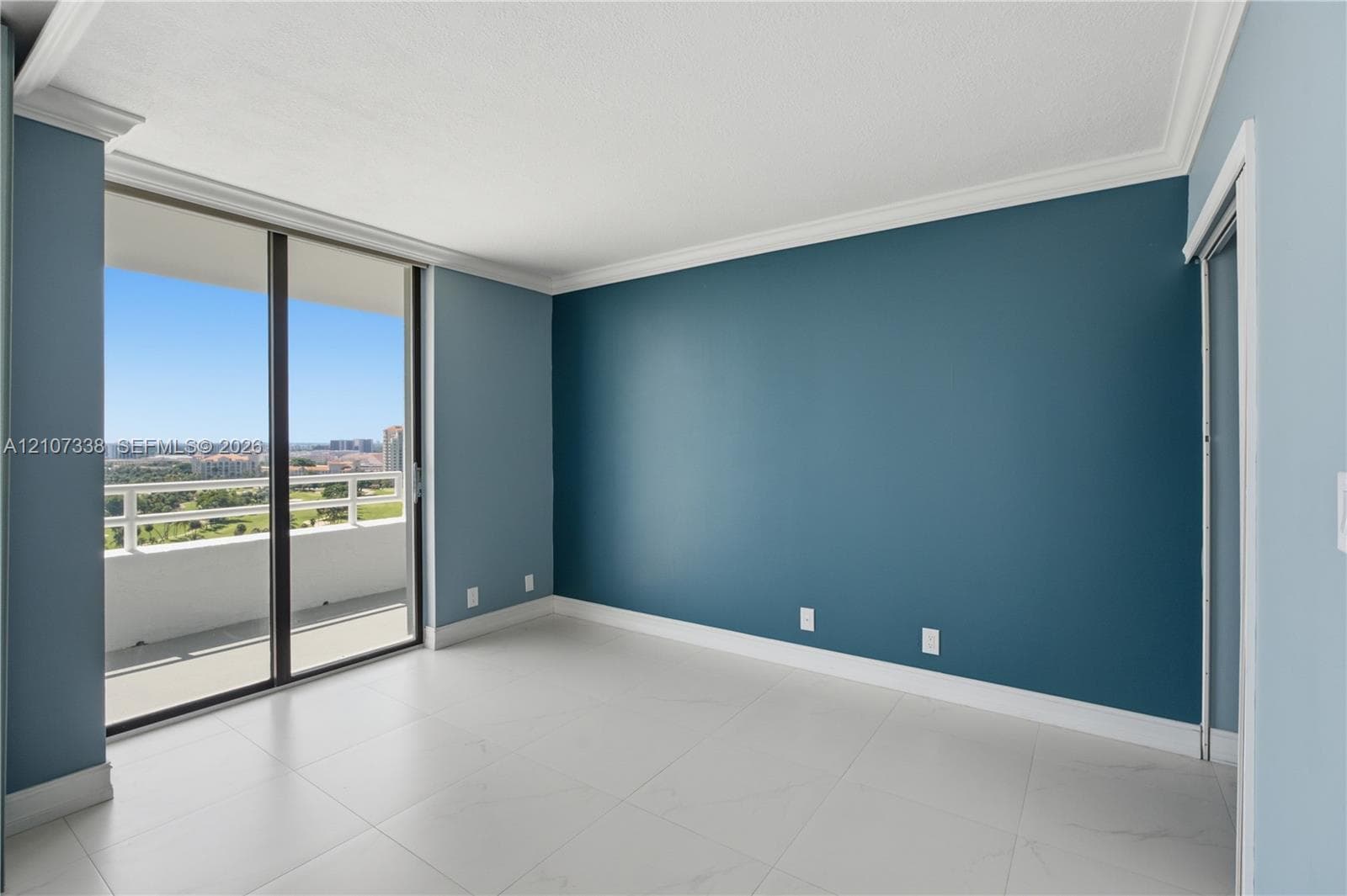 Floor-to-ceiling sliding glass doors, private balcony, large-format tile flooring, and crown molding