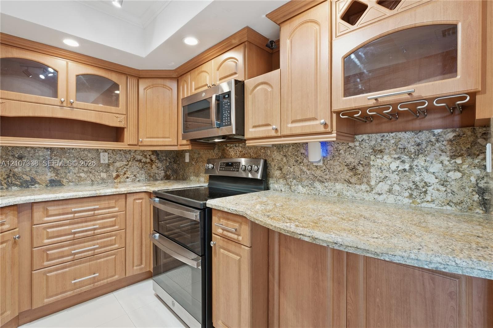 Kitchen featuring wood cabinetry, stone countertops, integrated wine glass rack, stainless steel double oven, and built-in microwave