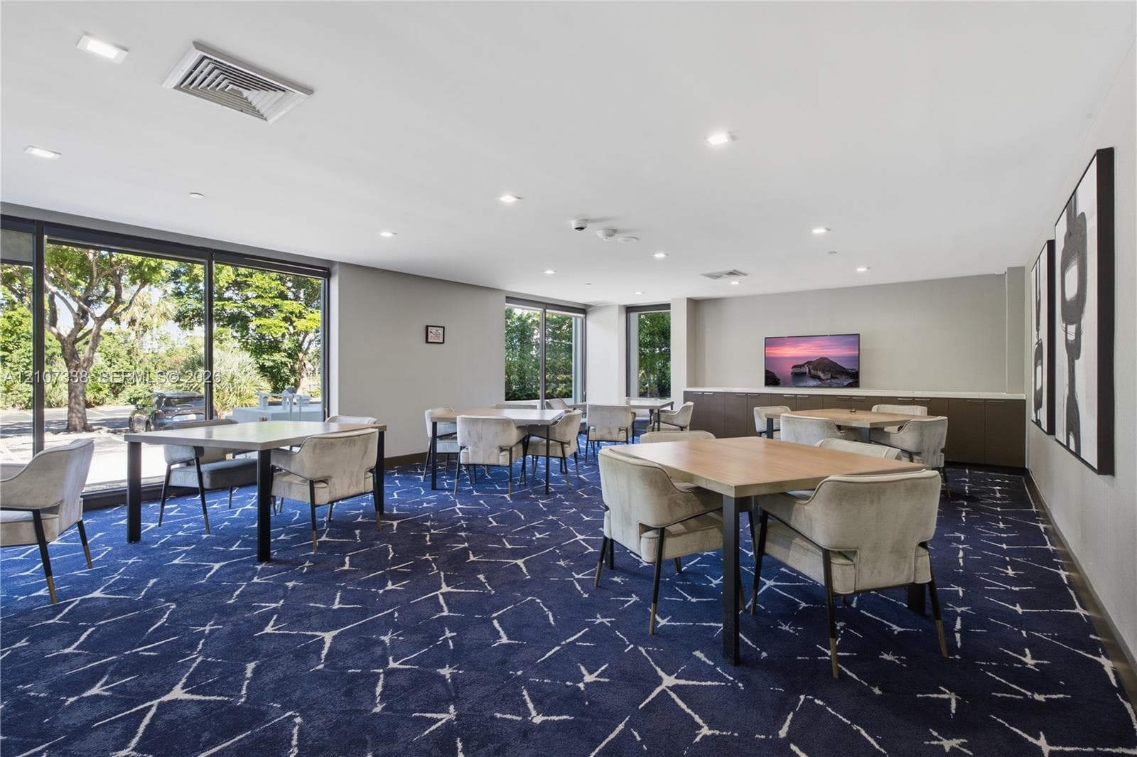 Multipurpose common area featuring expansive floor-to-ceiling glass windows, recessed ceiling lighting, and built-in cabinetry