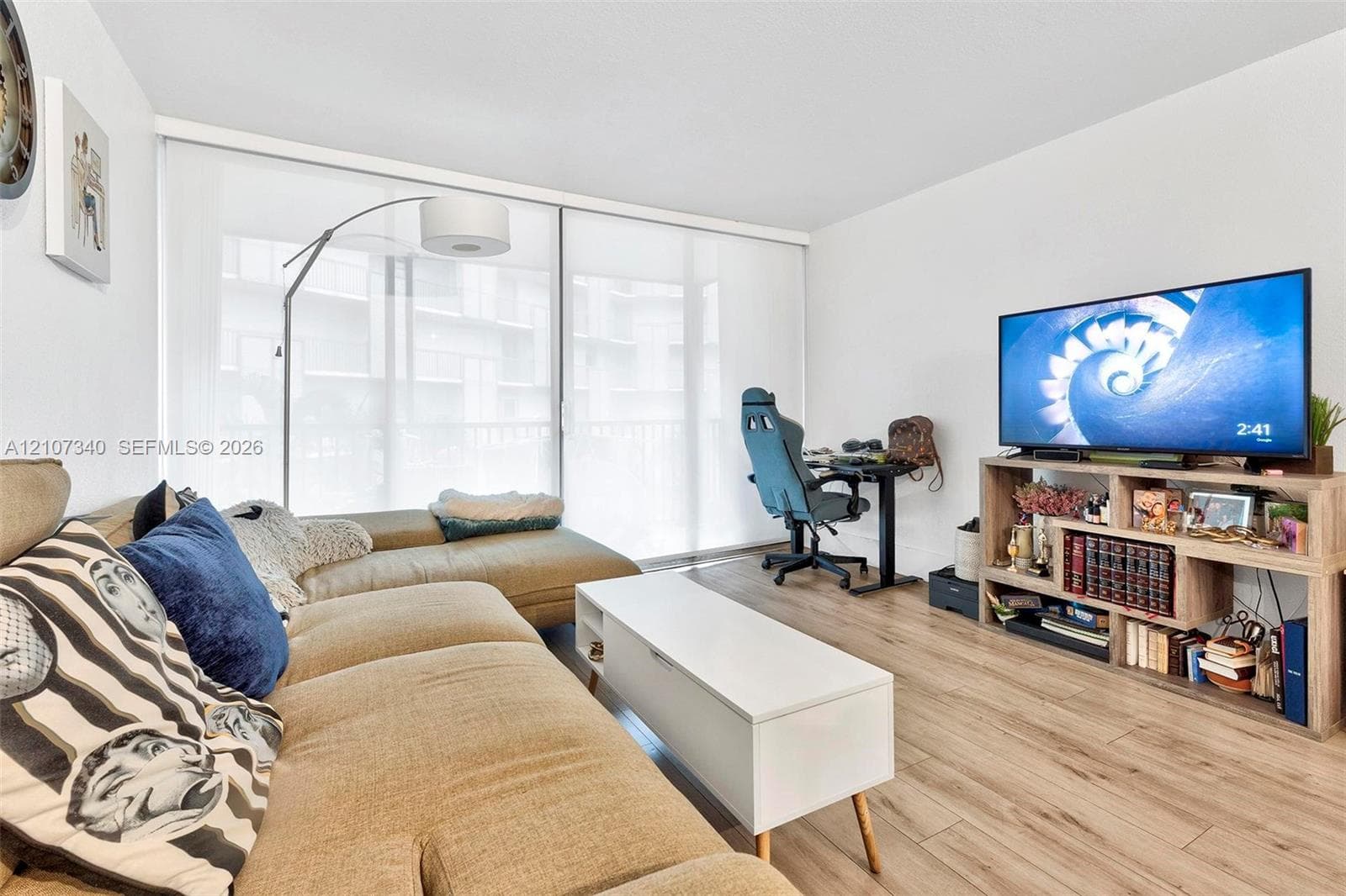 Living area featuring wood-finish flooring and expansive floor-to-ceiling sliding glass doors with roller shades