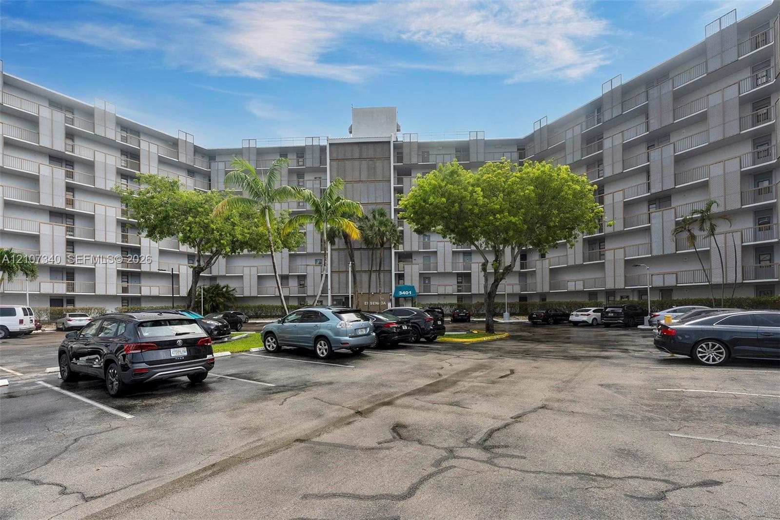 Multi-story residential building featuring a concrete façade with structural architectural screening and external balcony access
