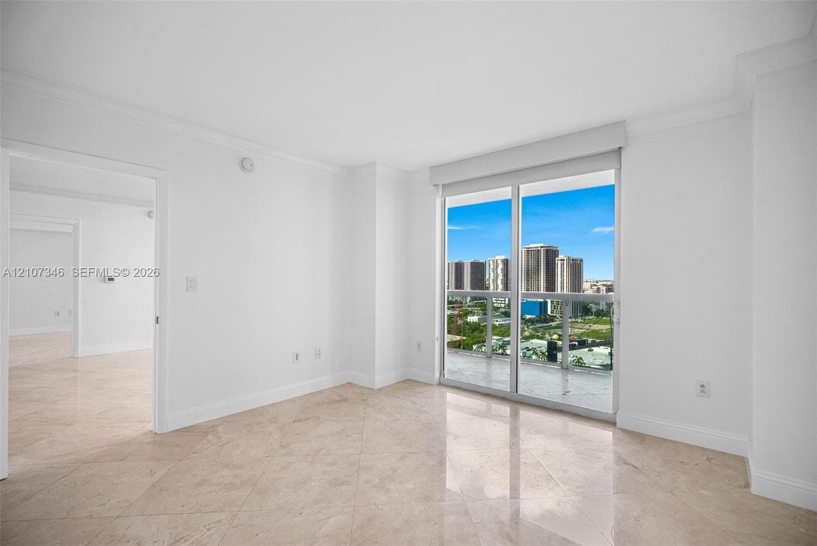 Neutral-toned stone flooring, sliding glass door, glass-paneled balcony railing, and high-rise exterior backdrop
