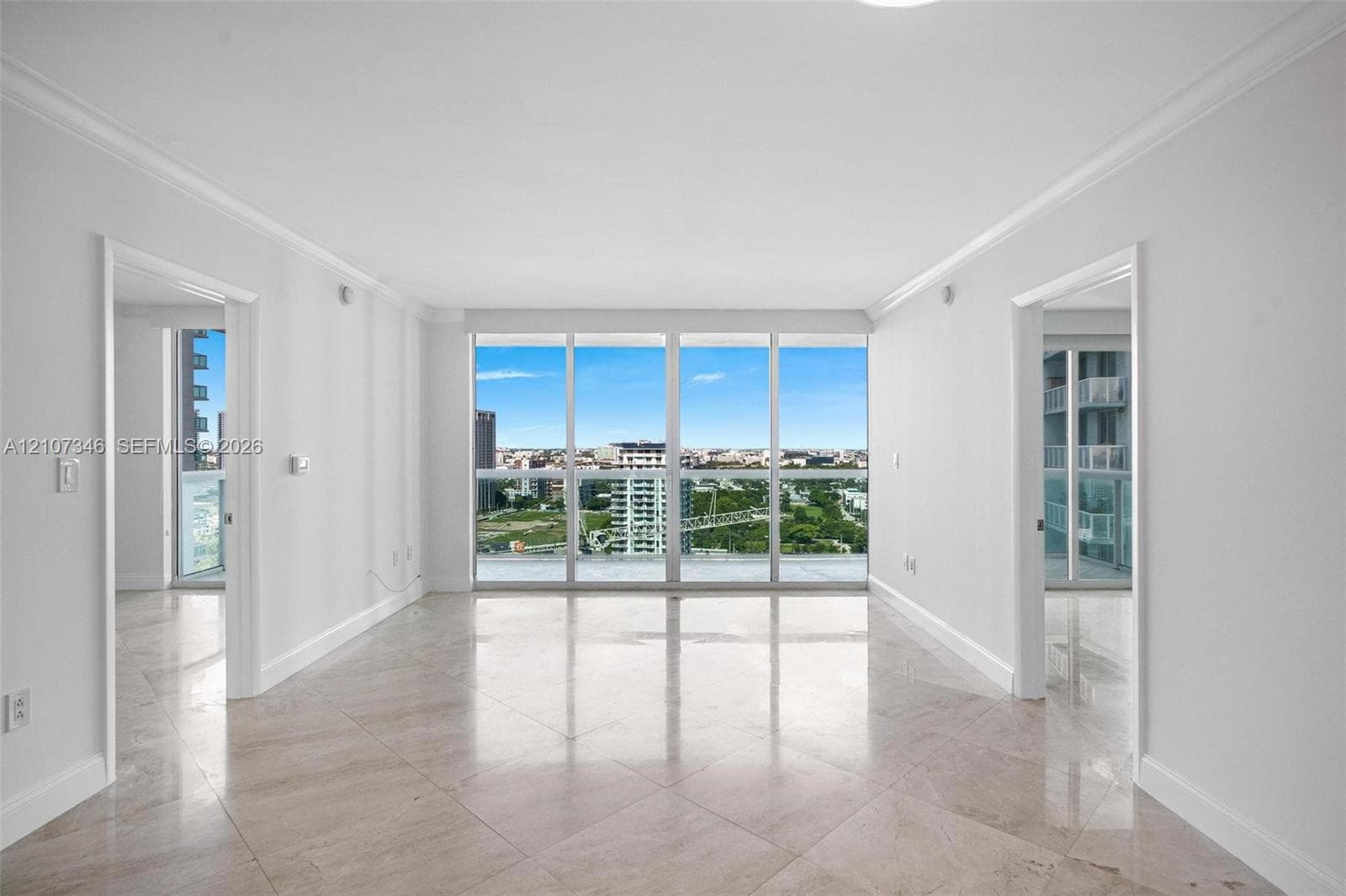Interior space featuring floor-to-ceiling windows, polished stone tile flooring, and crown molding