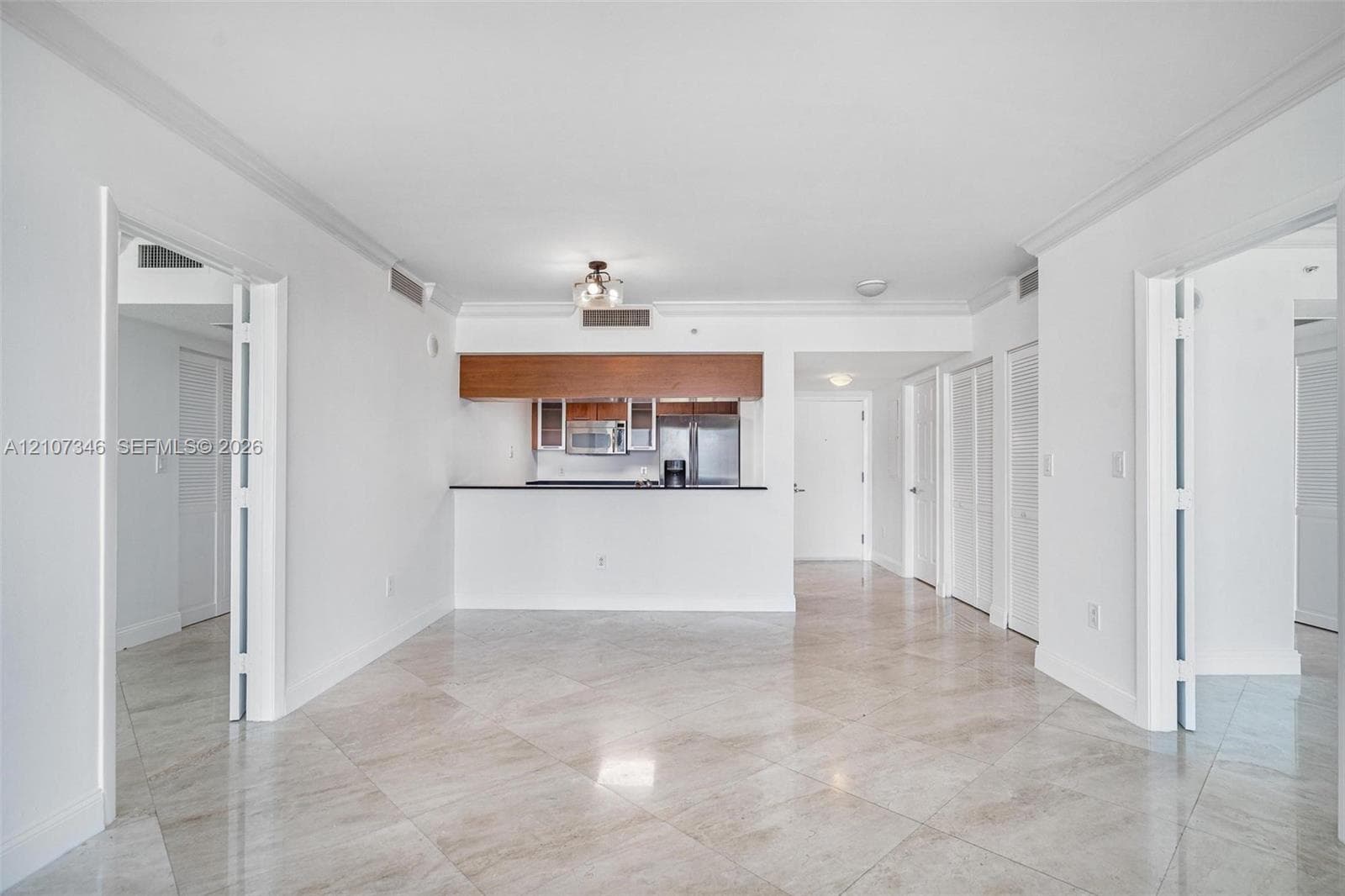 Open floor plan featuring stone-finish tile flooring, pass-through breakfast bar, stainless steel appliances, and crown molding