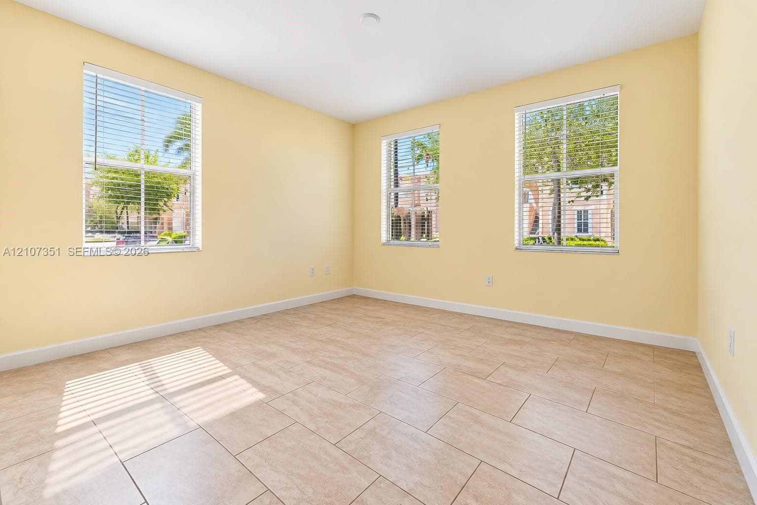 Room featuring tile flooring and three windows with built-in horizontal blinds