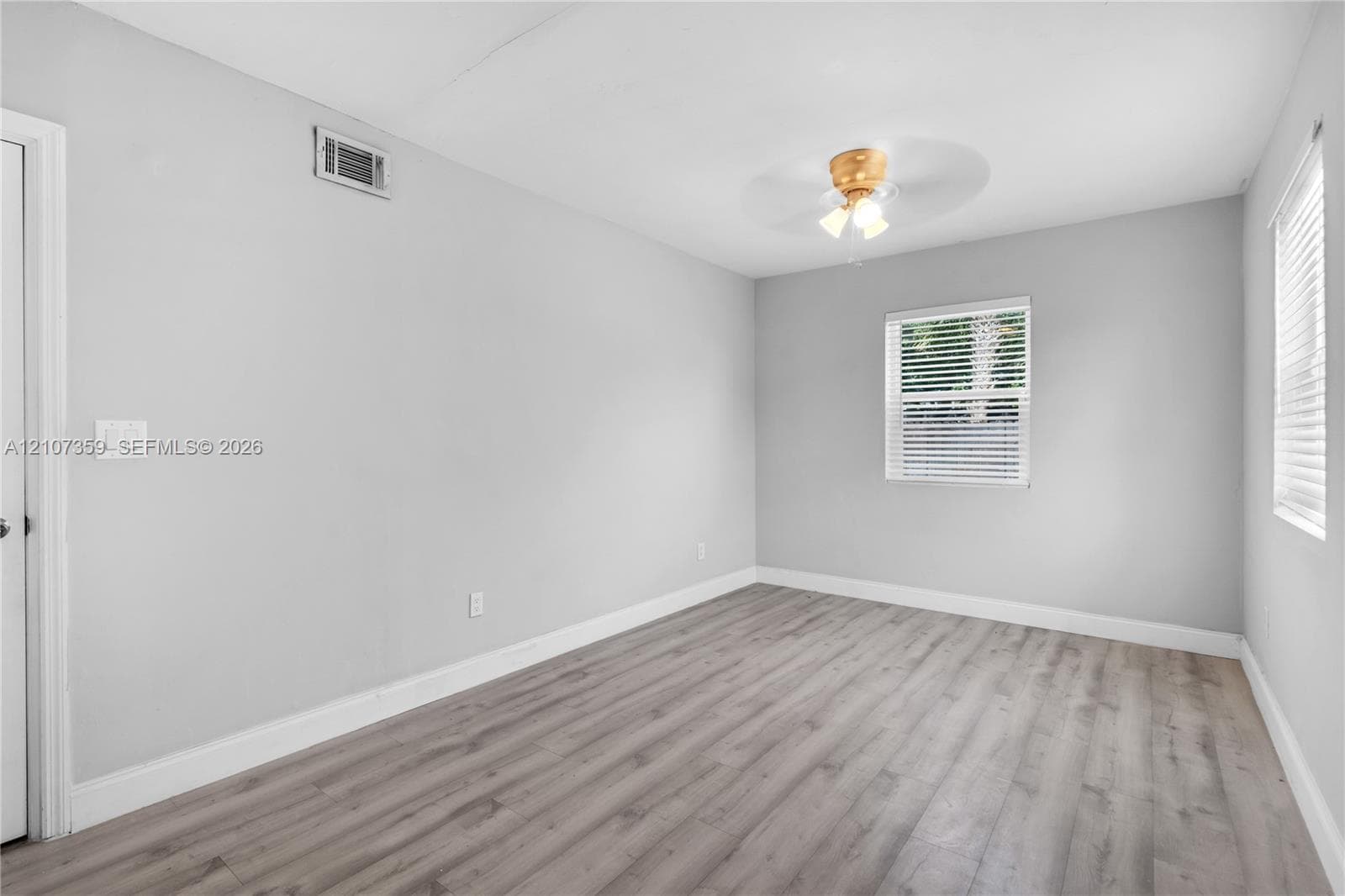 Neutral-toned walls, ceiling-mounted light fixture, and windows featuring horizontal blinds