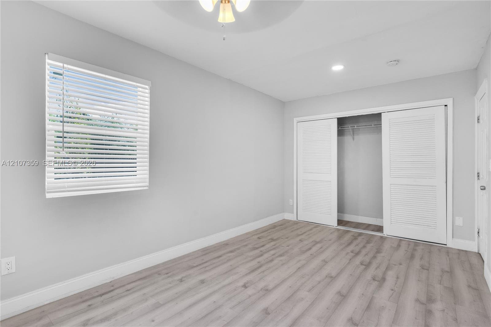 Bedroom with wood-look flooring, natural light, and neutral finishes.