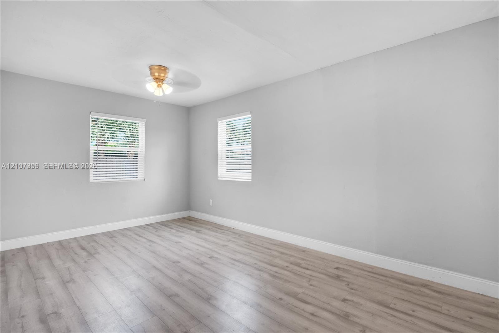 Bright bedroom with multiple windows, neutral finishes, and updated flooring.