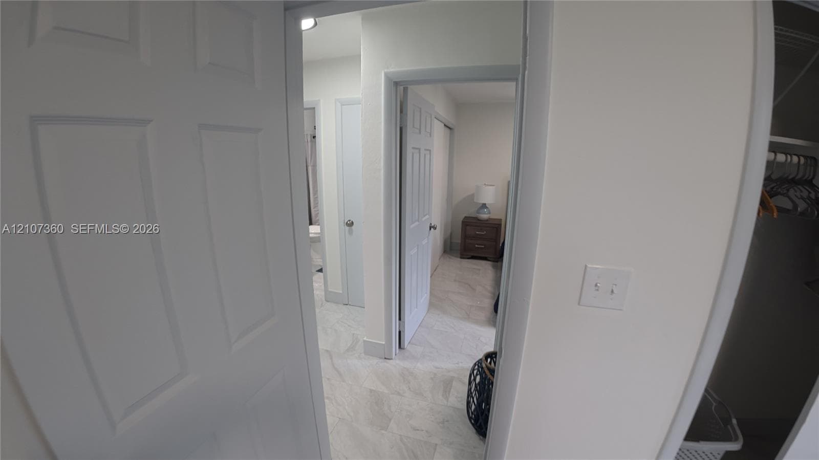 Interior featuring multi-panel interior doors, light-toned stone-patterned flooring, and a walk-in closet with integrated shelving