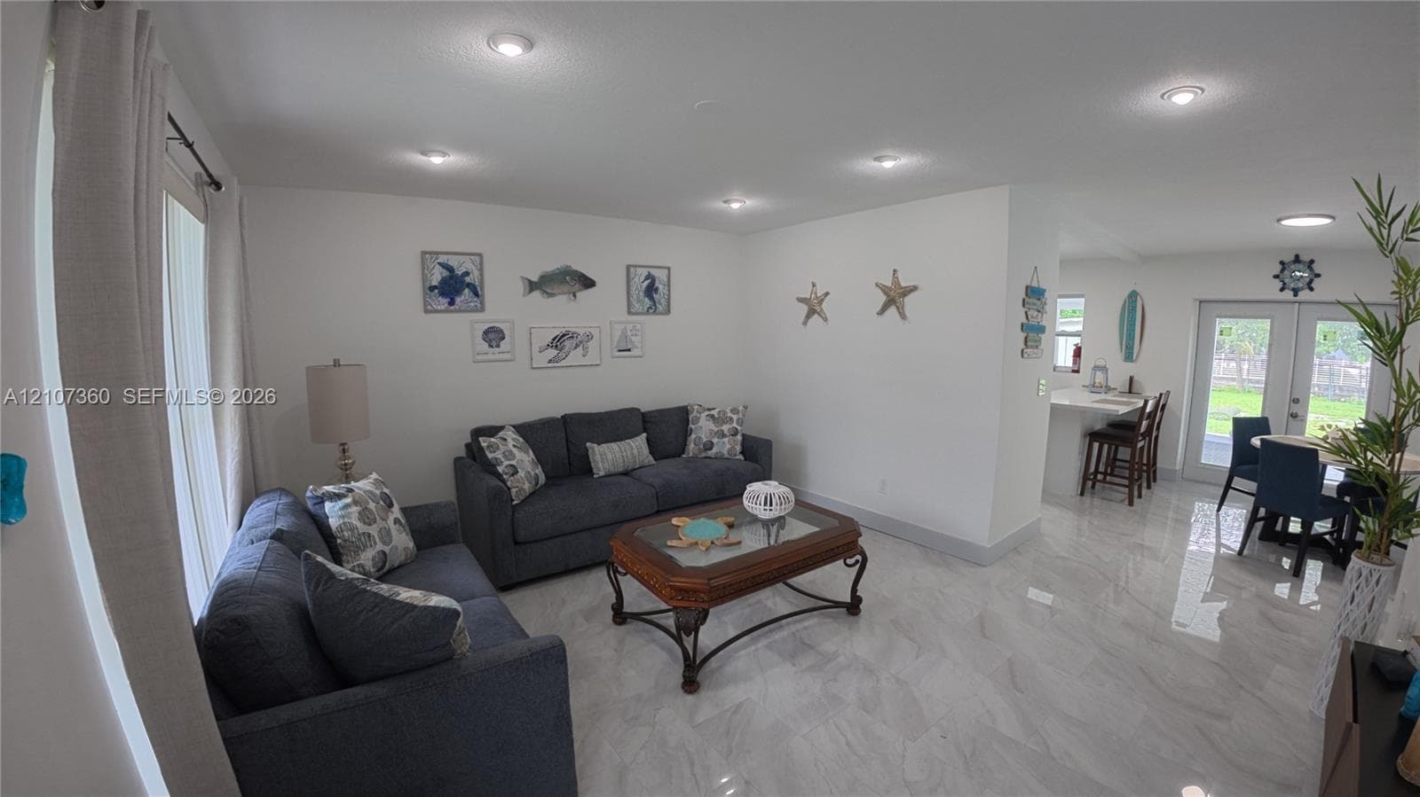 Open-concept interior featuring light-toned tile flooring, recessed ceiling lighting, and double-door access to the exterior