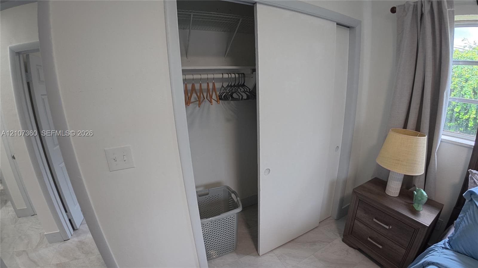 Sliding closet door with built-in overhead shelving and light-toned flooring