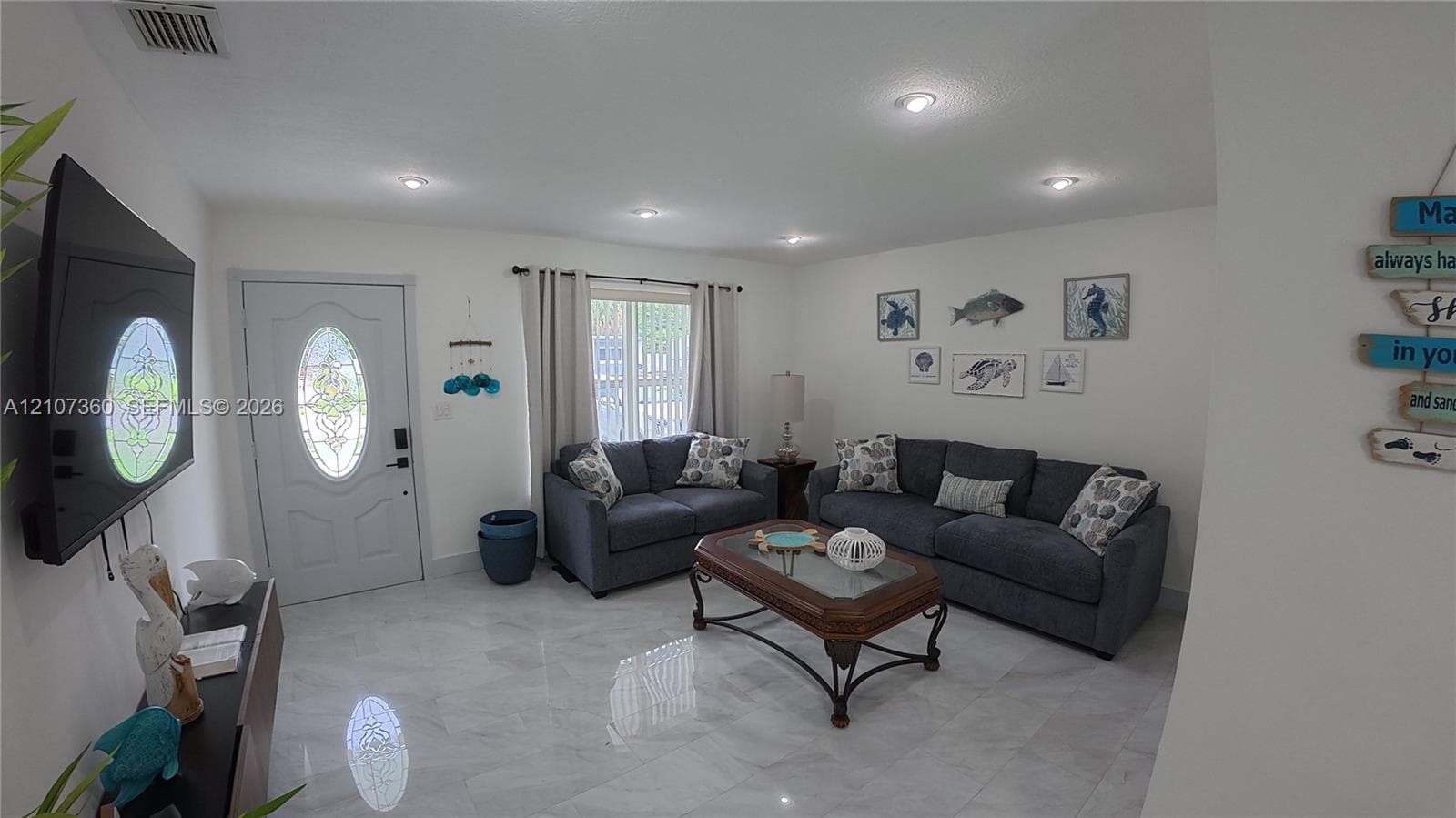 Living area featuring polished tile flooring, recessed lighting, and a front entry door with an oval stained-glass insert