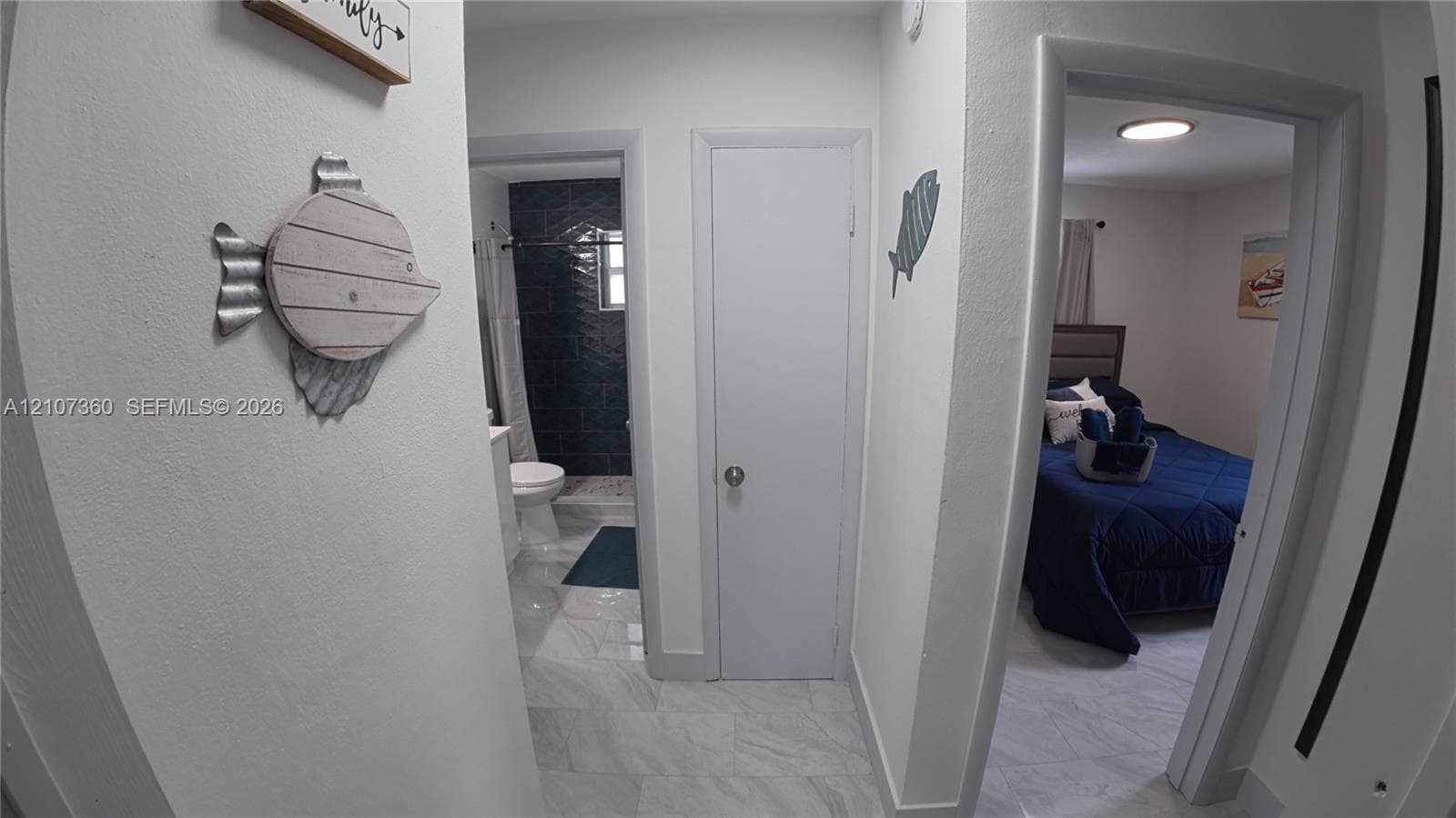 Hallway featuring white stone-finish flooring, two interior doors with round hardware, and recessed ceiling lighting