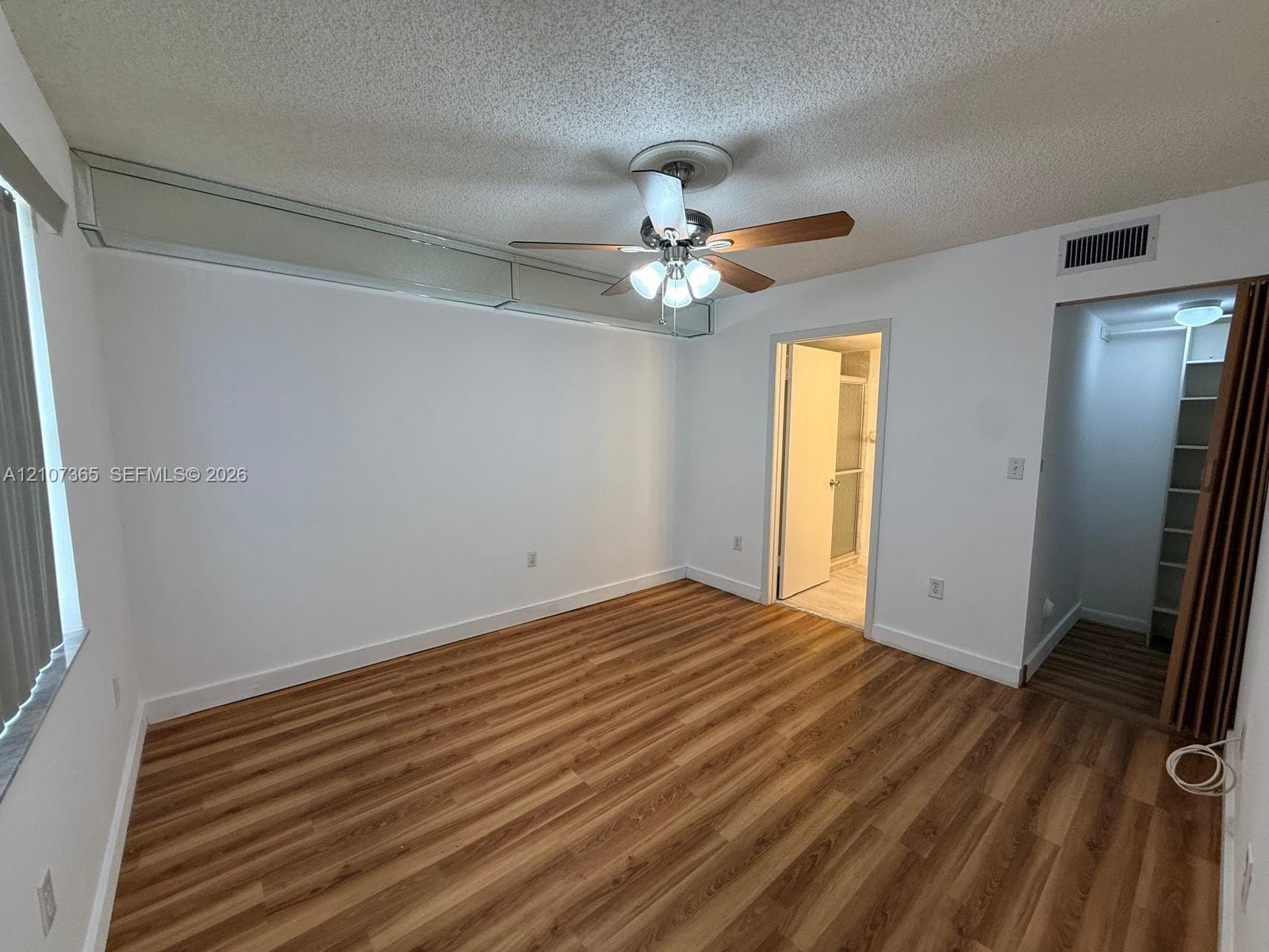 Wood-finish flooring, ceiling fan with integrated lighting, and built-in closet shelving