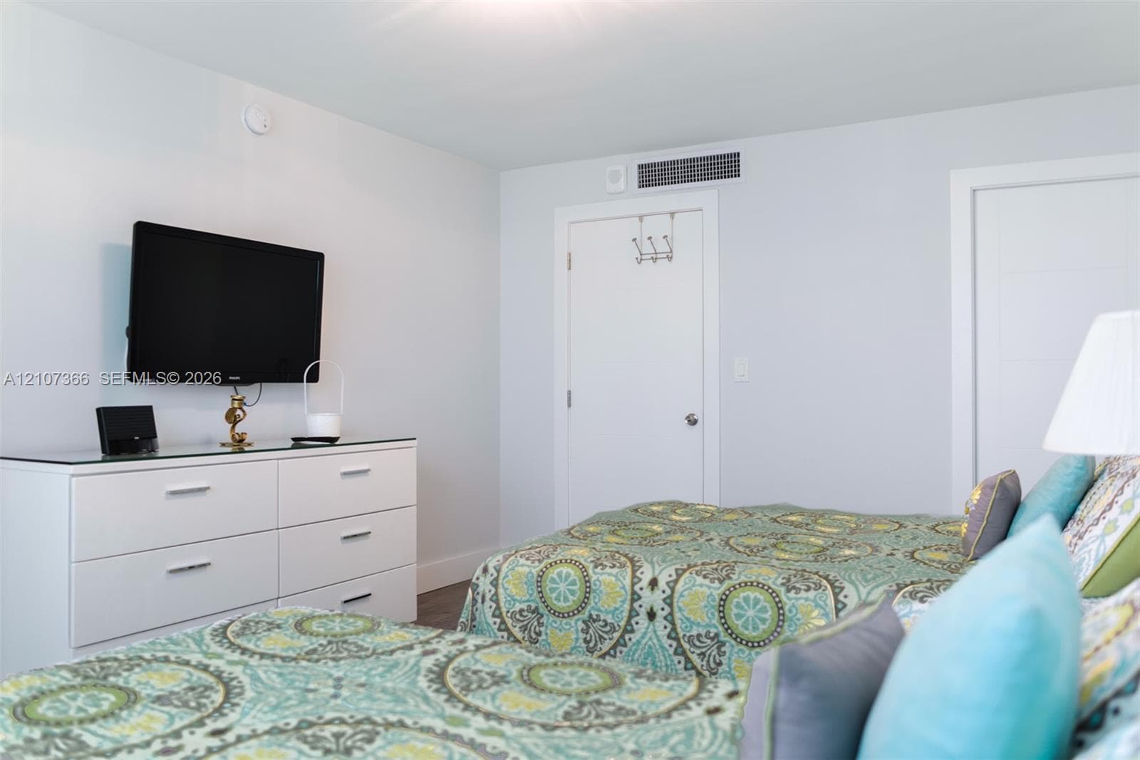 Neutral-toned interior space featuring light-colored walls, multi-panel doors, and wood-finish flooring