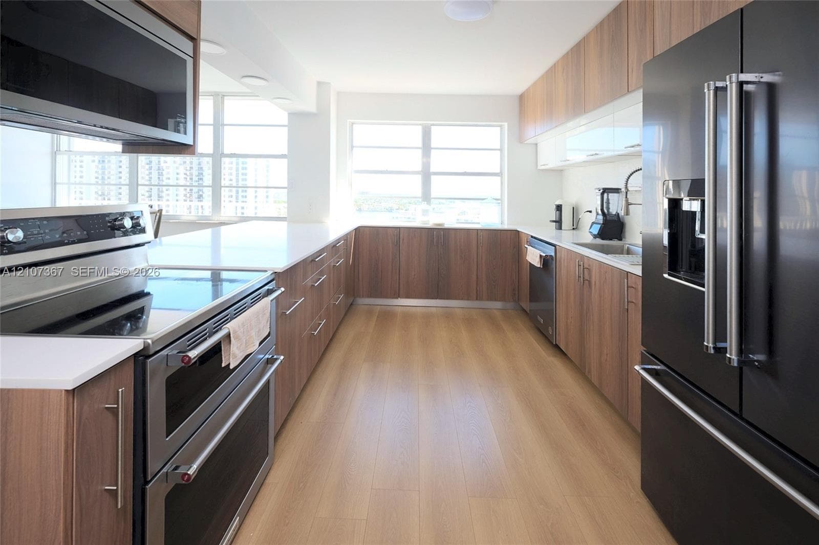 Entryway featuring wood-finish flooring, a dark-finish solid core door with a matte metallic handle, and a built-in recessed niche