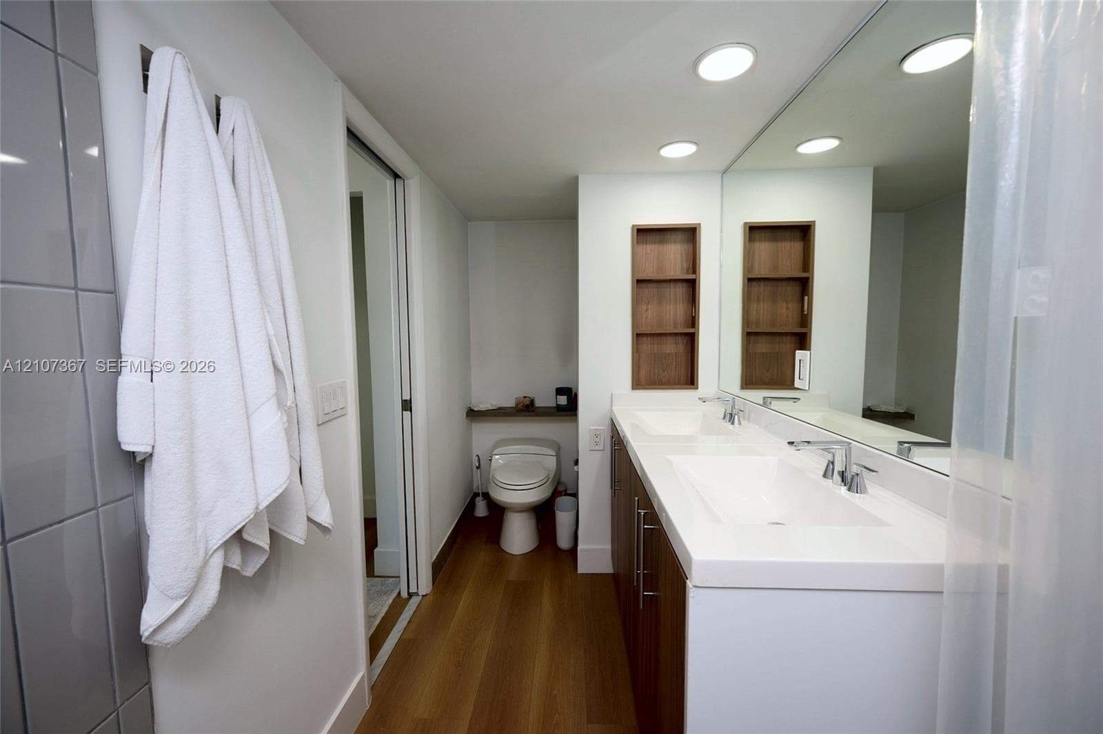 Built-in white shelving unit with multiple open storage compartments and wood-finish flooring