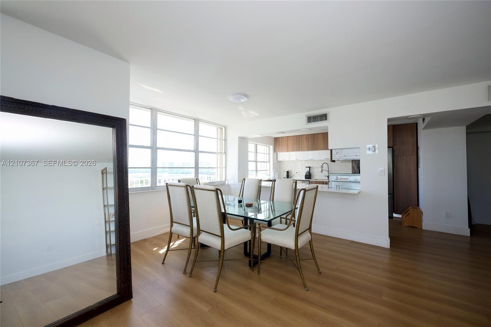 Kitchen featuring white solid-surface countertops, two-tone wood-finish and high-gloss white cabinetry, stainless steel appliances, and a high-arch pull-down faucet