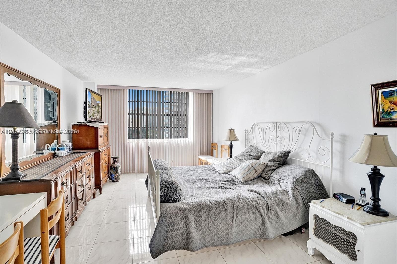 Neutral-toned interior featuring large-format tile flooring, textured ceiling, and floor-to-ceiling vertical blinds covering an expansive window