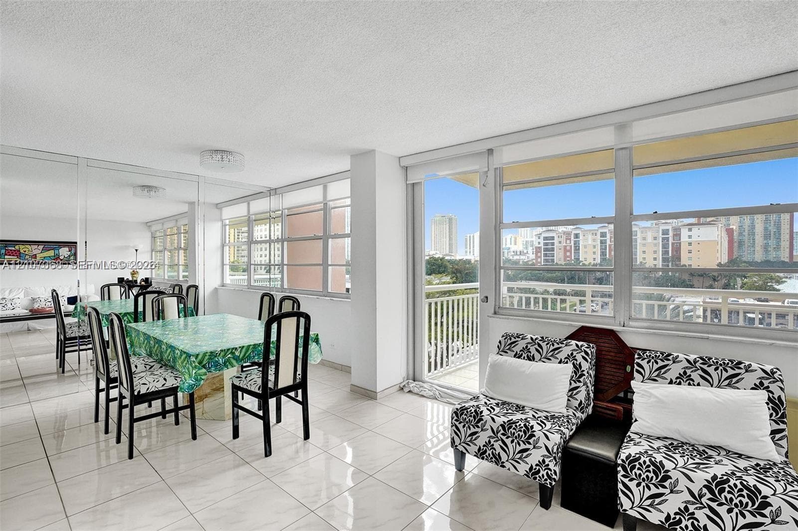Light-filled interior featuring expansive floor-to-ceiling windows, polished tile flooring, mirrored wall accents, and a private balcony