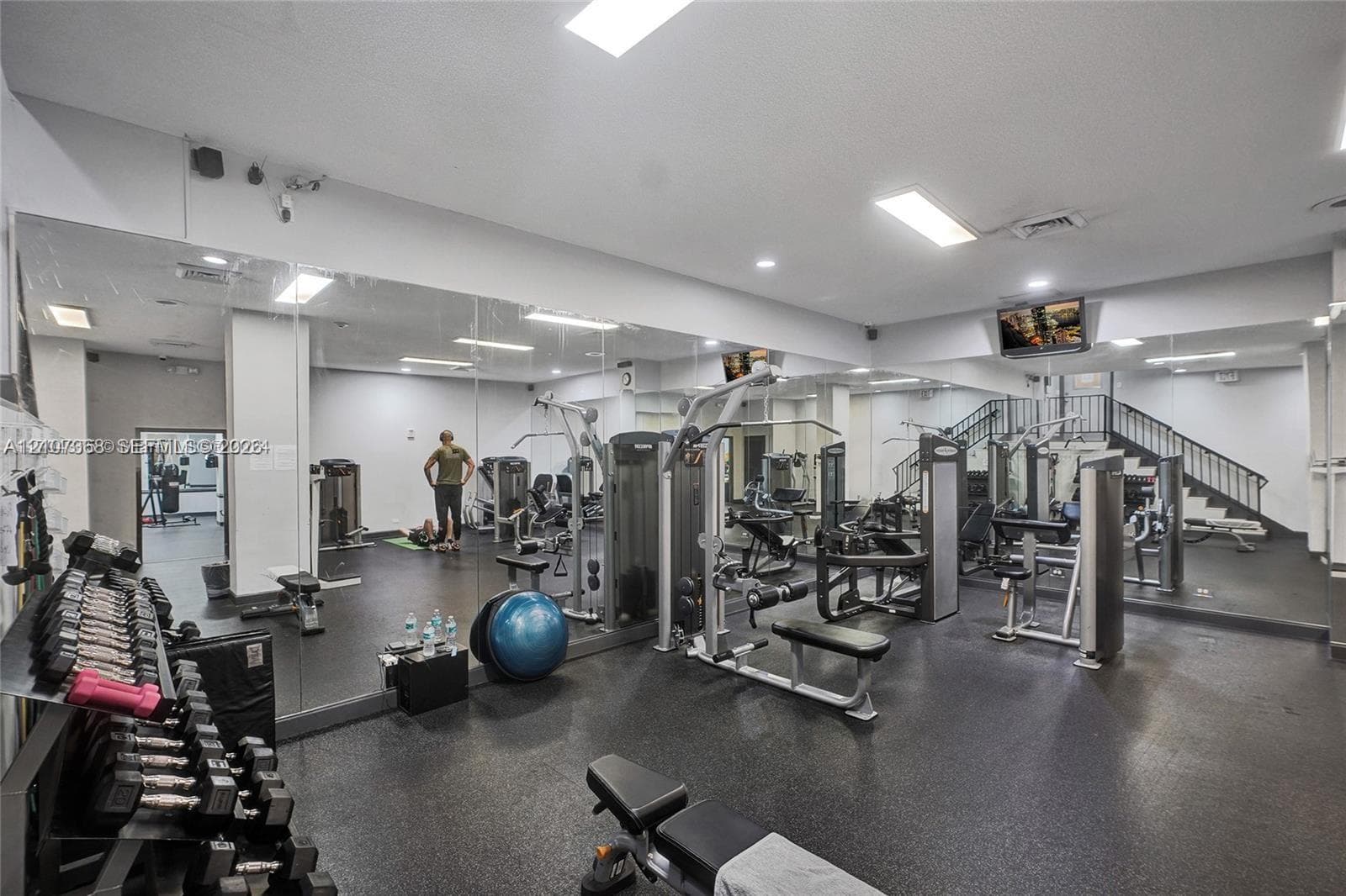 Fitness center featuring wall-to-wall mirrors, recessed lighting, and durable rubberized flooring