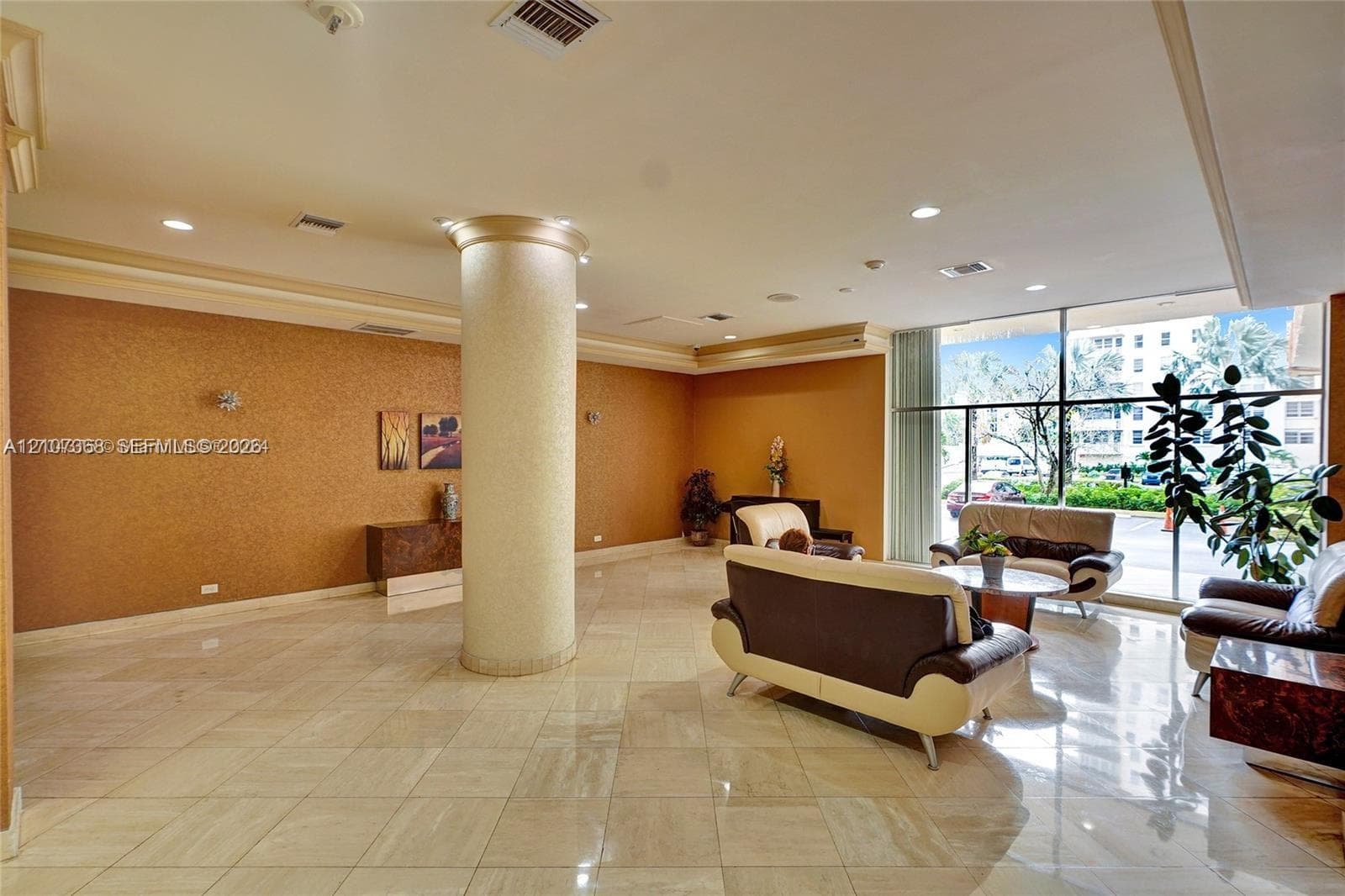 Lobby area featuring polished stone tile flooring, a prominent structural column, textured wall finishes, recessed ceiling lighting, and floor-to-ceiling windows