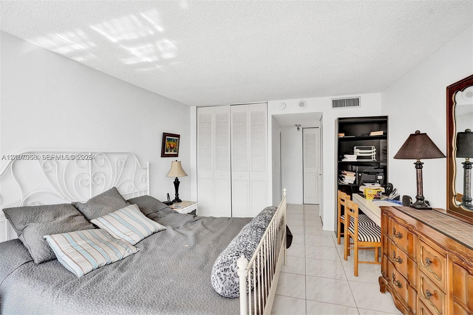 Neutral interior space featuring polished tile flooring, double-door louvered closet, and built-in shelving