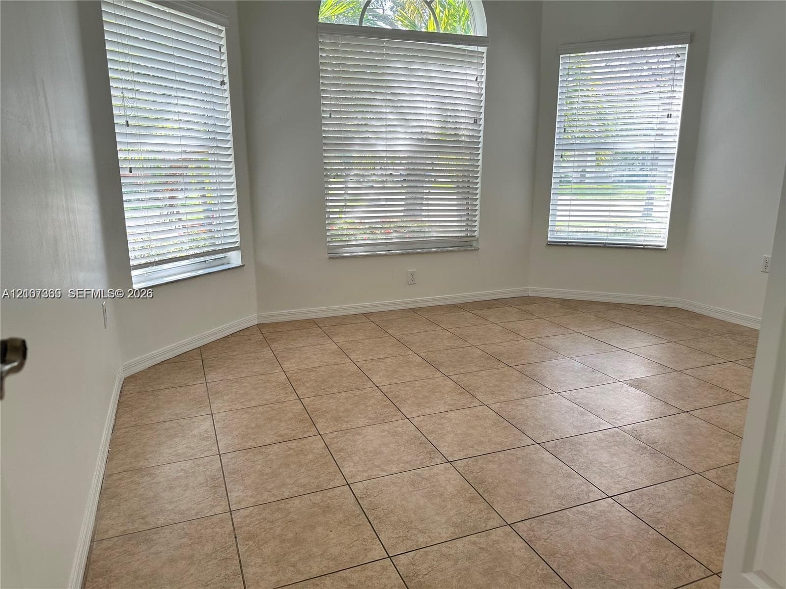 Polygonal room featuring tile flooring, three large windows, and a central arched window