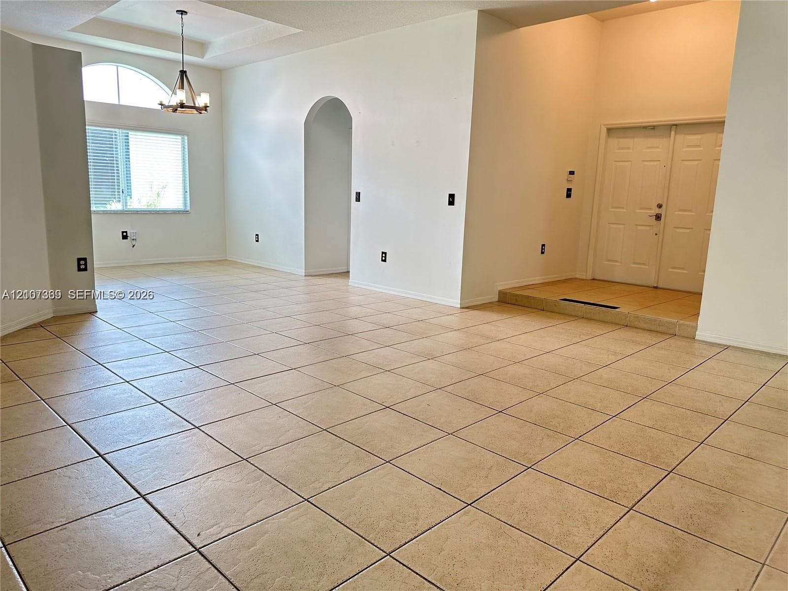 Open-concept interior featuring vaulted ceilings, arched entryways, tile flooring, and an arched window