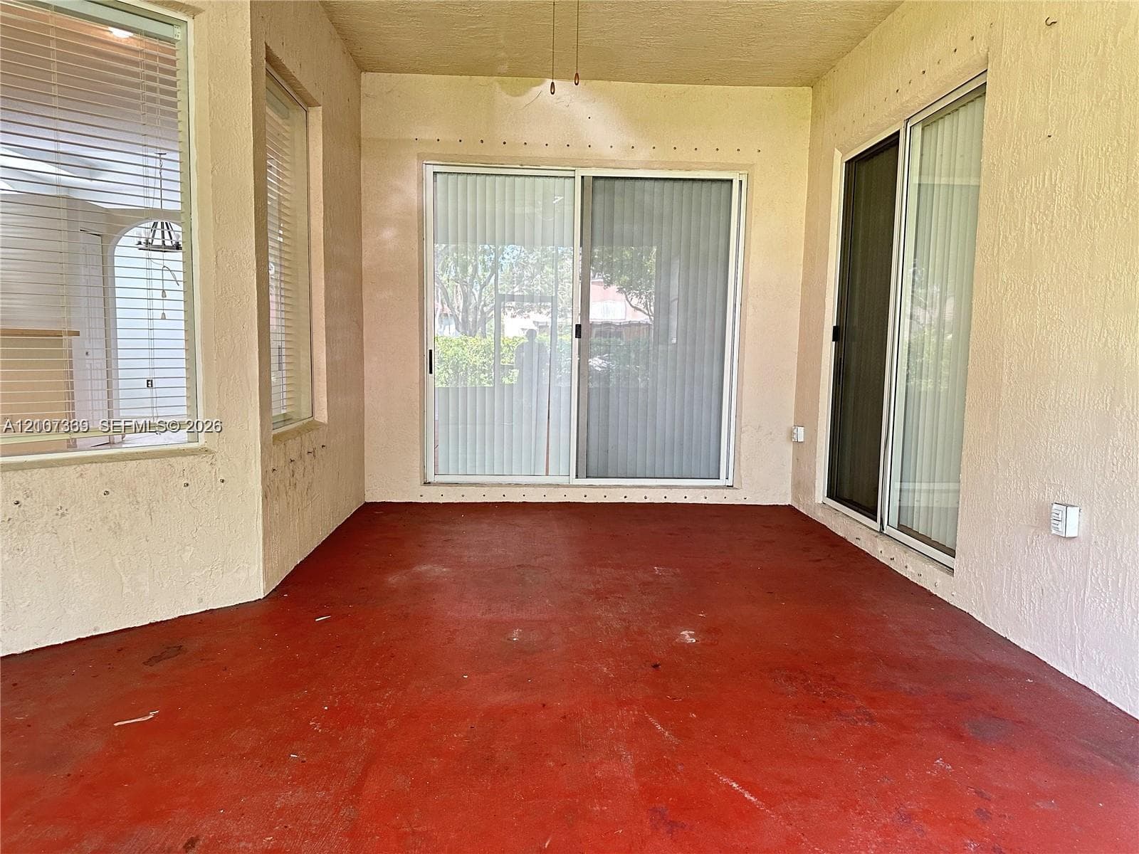Covered patio featuring concrete flooring, textured walls, and large sliding glass doors