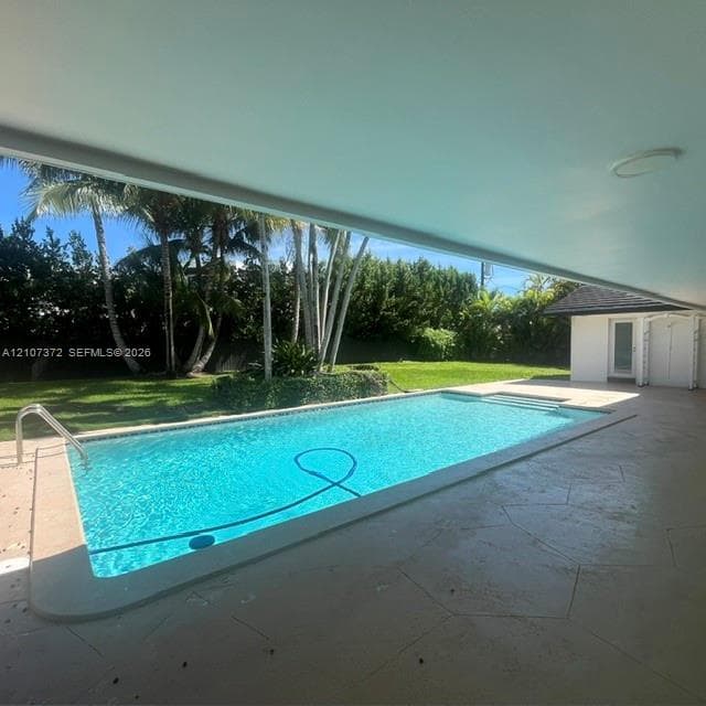 Expansive backyard featuring a grass lawn, mature palm trees, perimeter fencing, and a stone-bordered fire pit