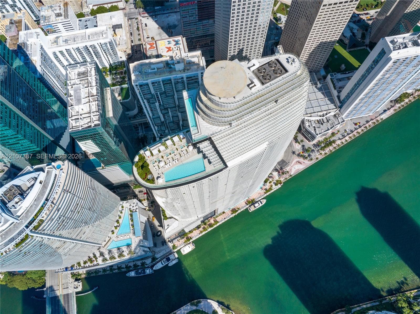 High-rise residential tower featuring a rooftop swimming pool, terrace, and water frontage
