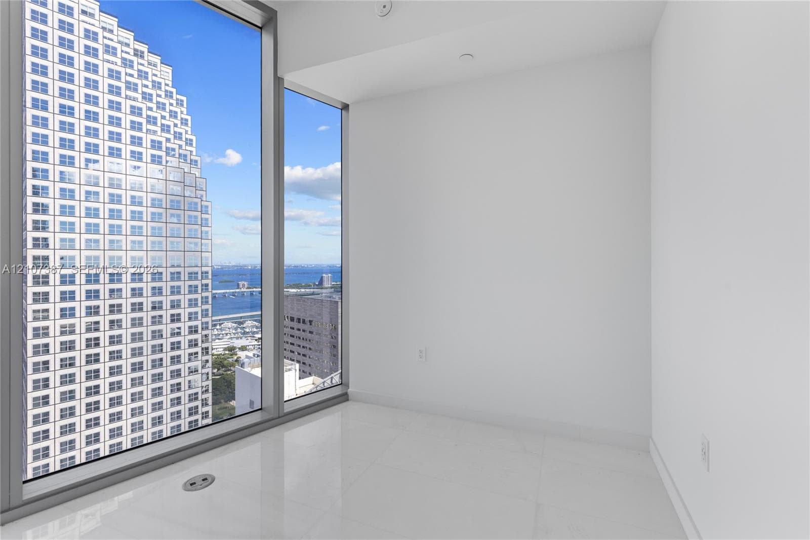 Floor-to-ceiling windows featuring expansive urban and water scenery, complemented by crisp white walls and light-toned tile flooring