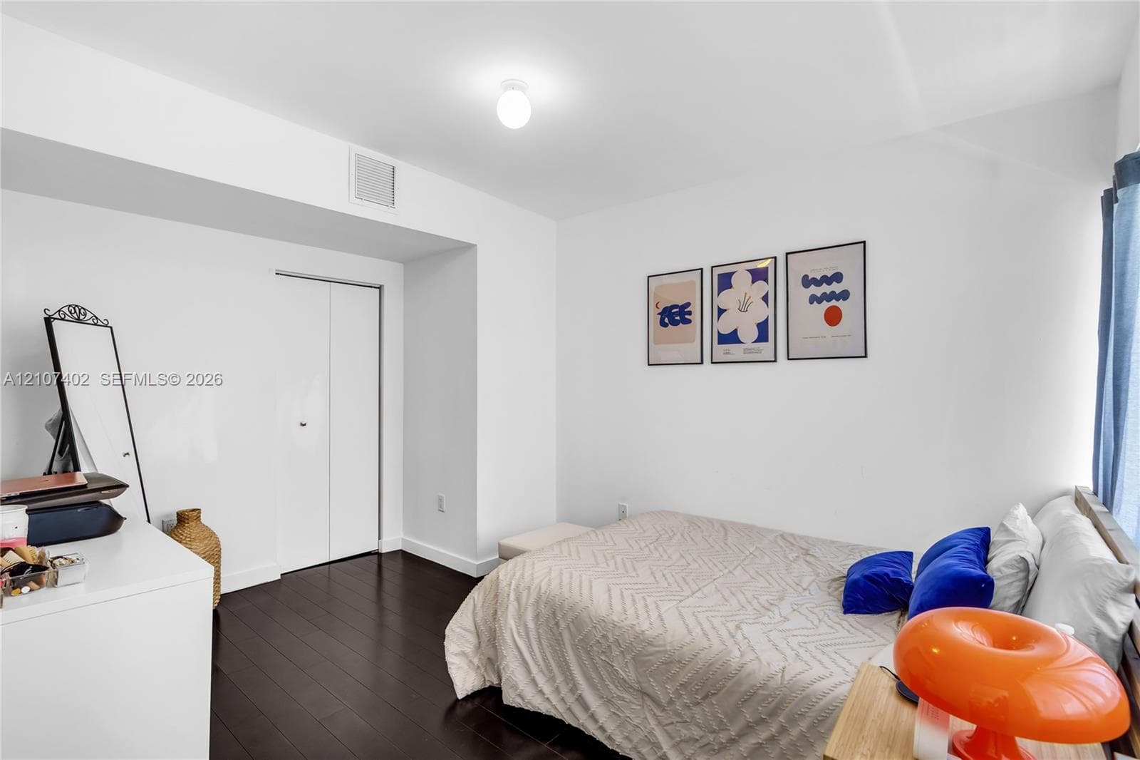 Room featuring dark wood-finish flooring, white walls, and a recessed closet with bi-fold doors