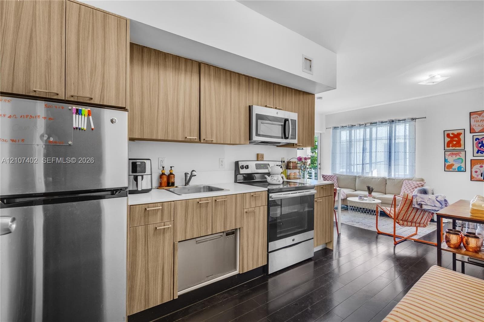 Kitchen featuring wood-finish cabinetry, stainless steel appliances, solid-surface countertops, and dark hardwood flooring