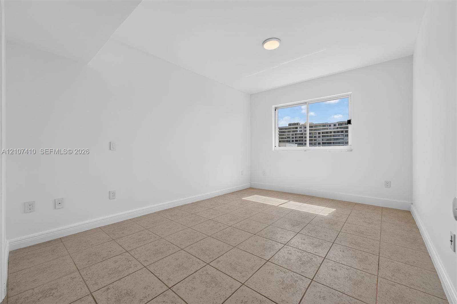Interior room featuring neutral wall-to-wall ceramic tile flooring, smooth white walls, a flush-mount ceiling light, and a single sliding window