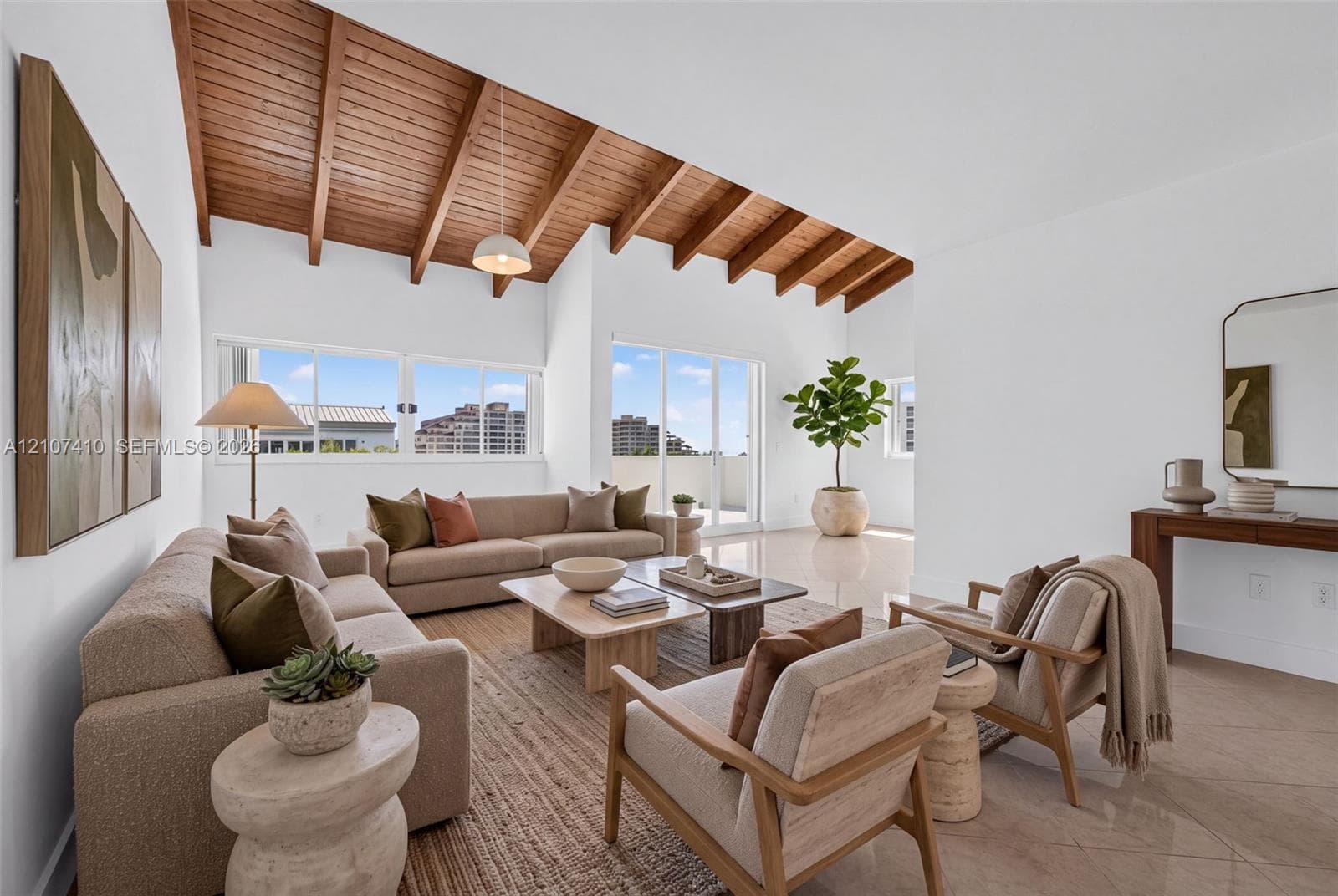 Vaulted ceiling with exposed wood beams, sliding glass doors, polished stone-finish flooring, and crisp white walls