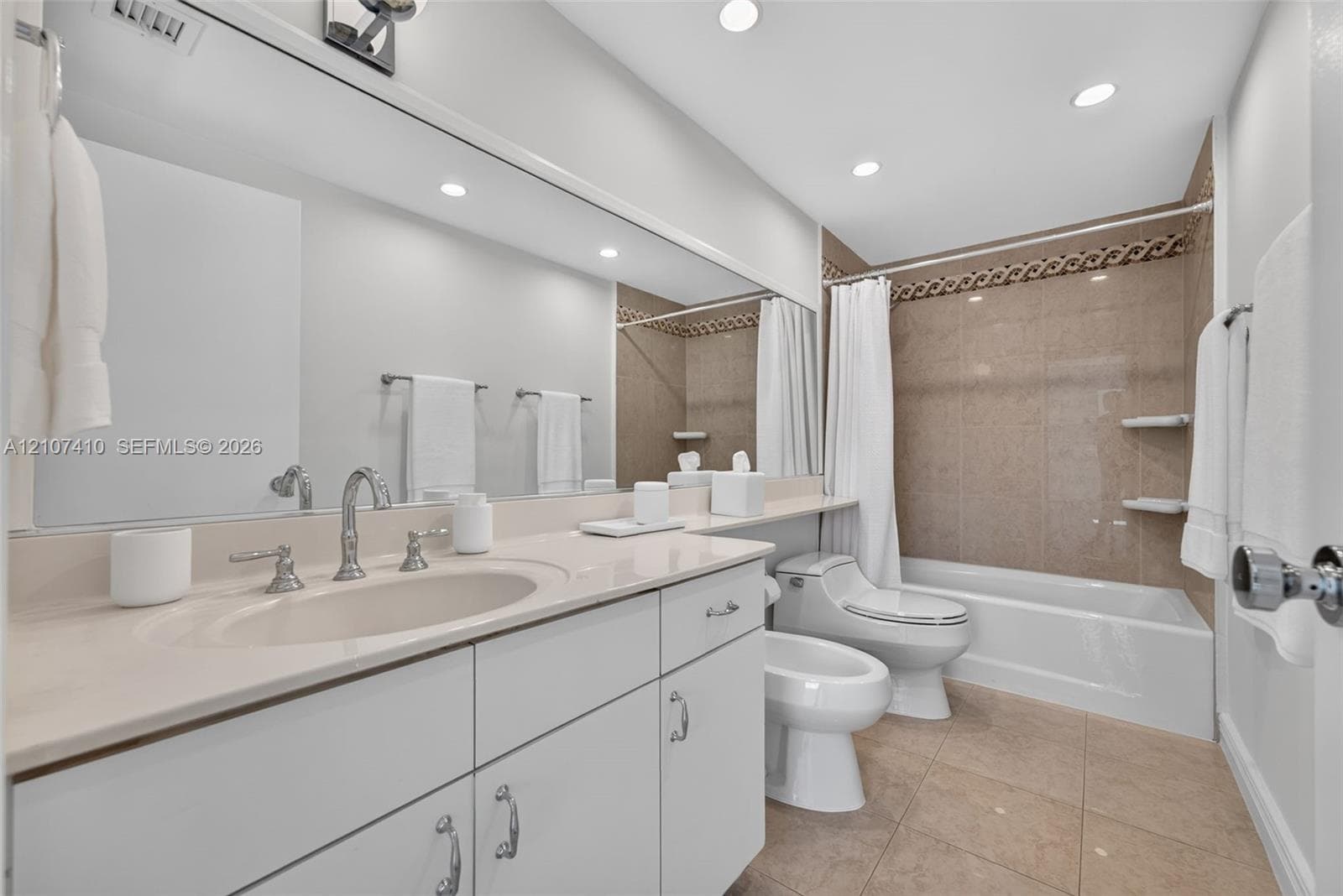 Bathroom featuring a solid-surface vanity countertop, full-width mirror, recessed lighting, tile flooring, and a shower-tub combination with integrated shelving
