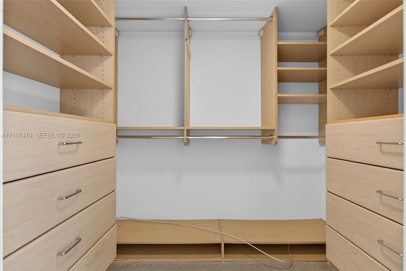 Customized closet storage featuring light wood-finish built-in cabinetry, multiple adjustable shelving units, integrated clothing rods, and soft-close drawers with polished metal hardware