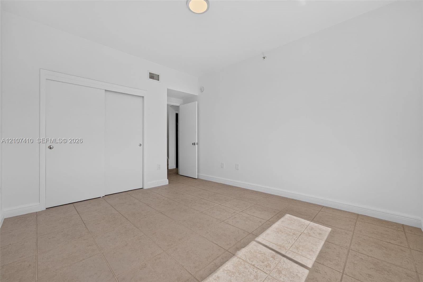 Interior room featuring neutral ceramic tile flooring, smooth wall finishes, sliding closet doors, and recessed ceiling lighting