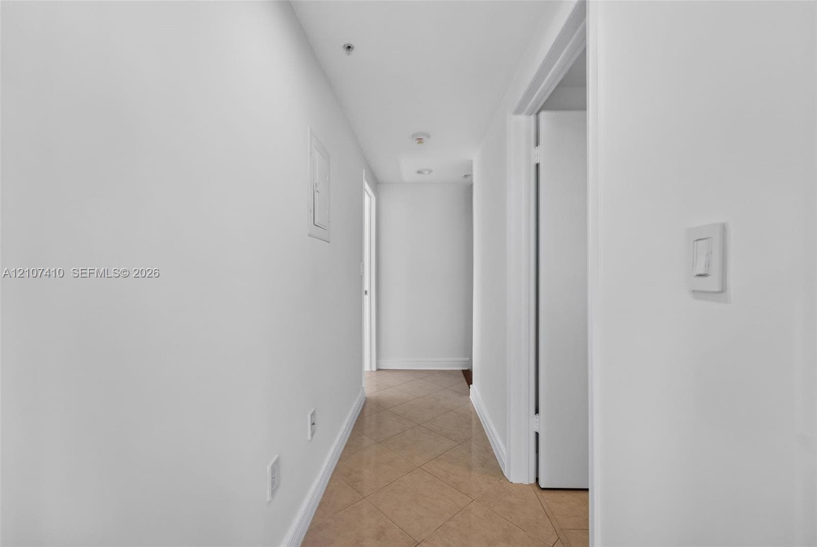 Neutral-toned hallway featuring diagonal-set tile flooring, crisp white wall finishes, and recessed ceiling lighting
