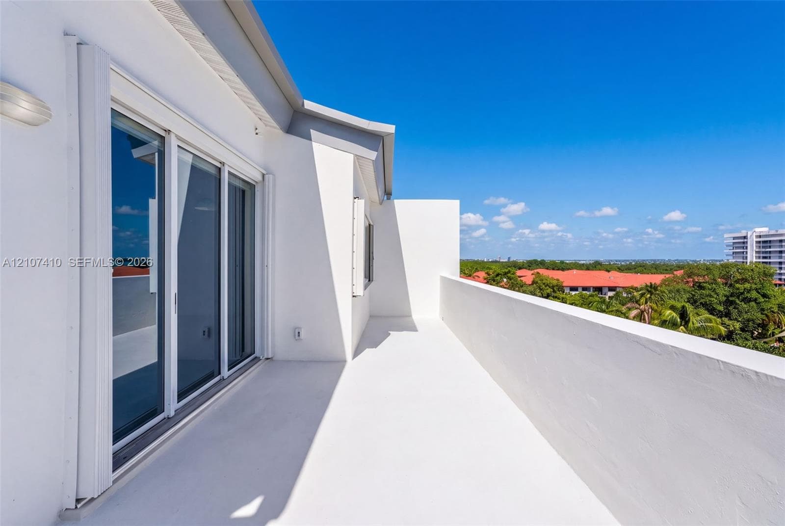 Private balcony featuring a solid concrete perimeter wall, smooth stucco finishes, and multi-panel sliding glass doors