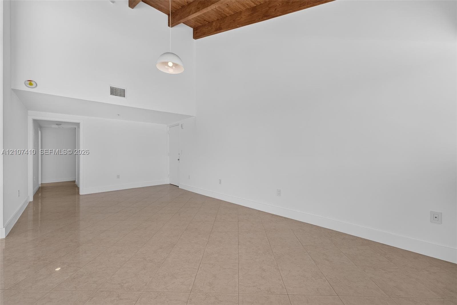 Vaulted ceiling featuring exposed wood beams, neutral tile flooring, and a suspended dome pendant light