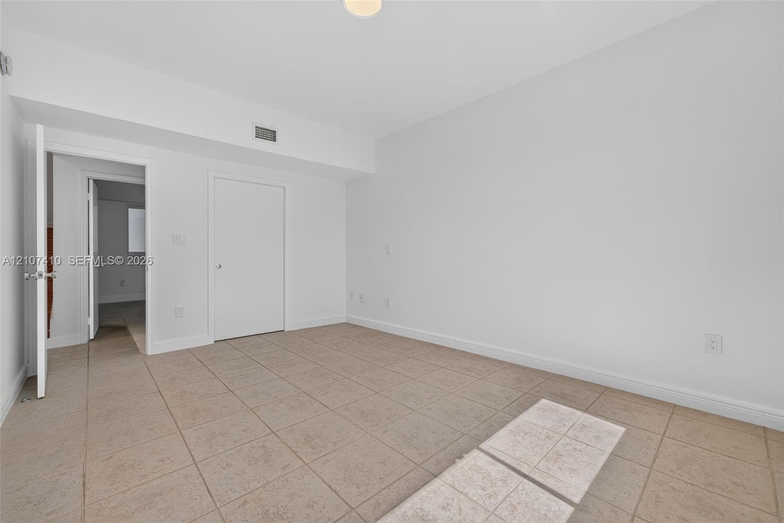 Interior space featuring neutral tile flooring, smooth white walls, solid-core interior doors, and overhead lighting