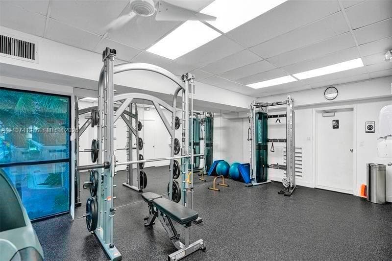 Exercise room featuring rubber flooring, recessed drop ceiling lighting, and floor-to-ceiling mirrored walls